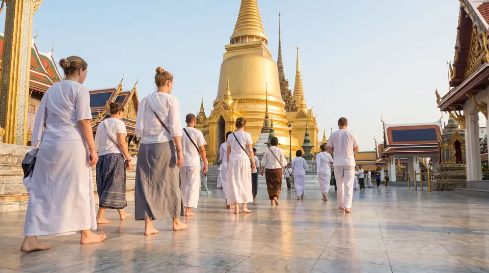 Visitors in modest clothes walking barefoot across a temple courtyard