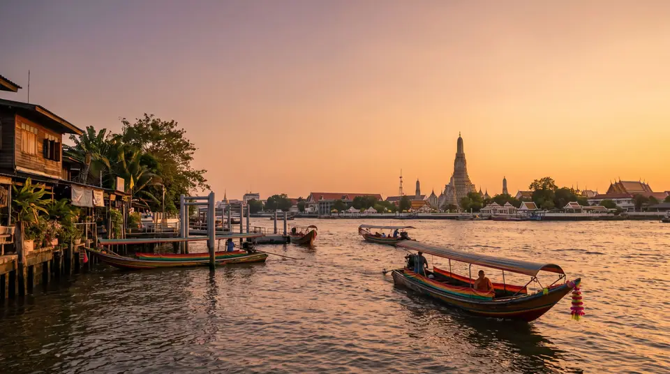 Chao Phraya River in Bangkok at golden hour, temple spires on the bank and a long-tail boat passing